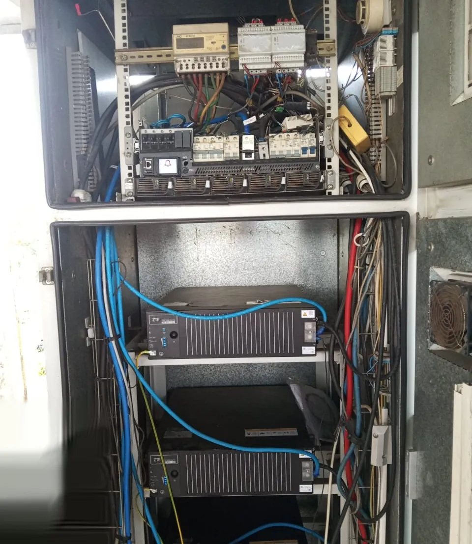 Armoire d'énergie ouverte : compteur, disjoncteurs et redresseurs en haut, batteries lithium ZTE en bas