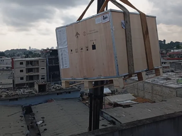 Caisse d'équipement hissée par une grue sur une toiture-terrasse à Abidjan