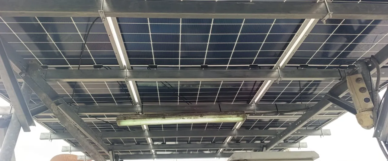 Rails et câblage sous les panneaux d'un auvent solaire, réglette d'éclairage et projecteur