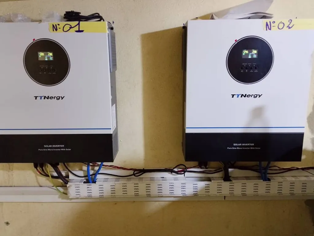 Deux onduleurs solaires hybrides numérotés 01 et 02, fixés au mur d'un local technique