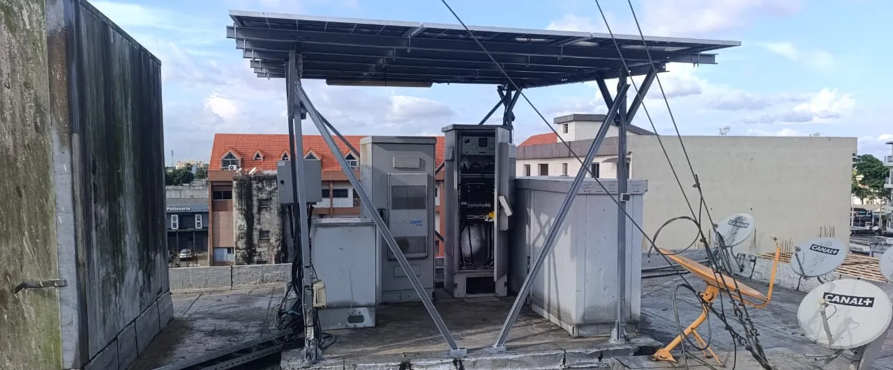 Armoire télécom ouverte entre deux shelters, sous l'auvent solaire d'un site en toiture