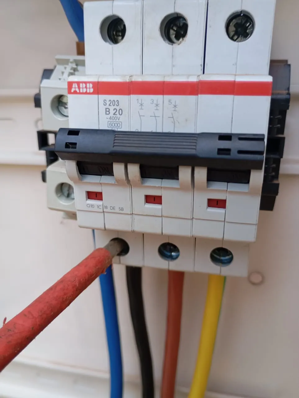 Disjoncteur ABB triphasé 20 A et ses câbles d'alimentation, serrage contrôlé au tournevis